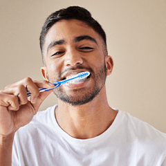 Man smiling while brushing his teeth