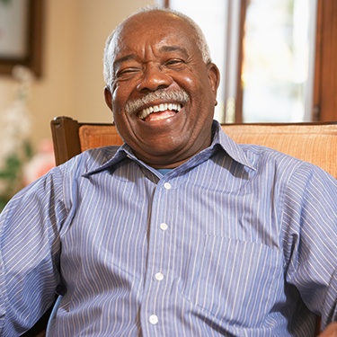 Older man smiling while seated after seeing an Aetna dentist in Sunnyvale