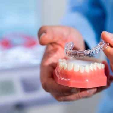 Dentist lifting an occlusal splint from model teeth