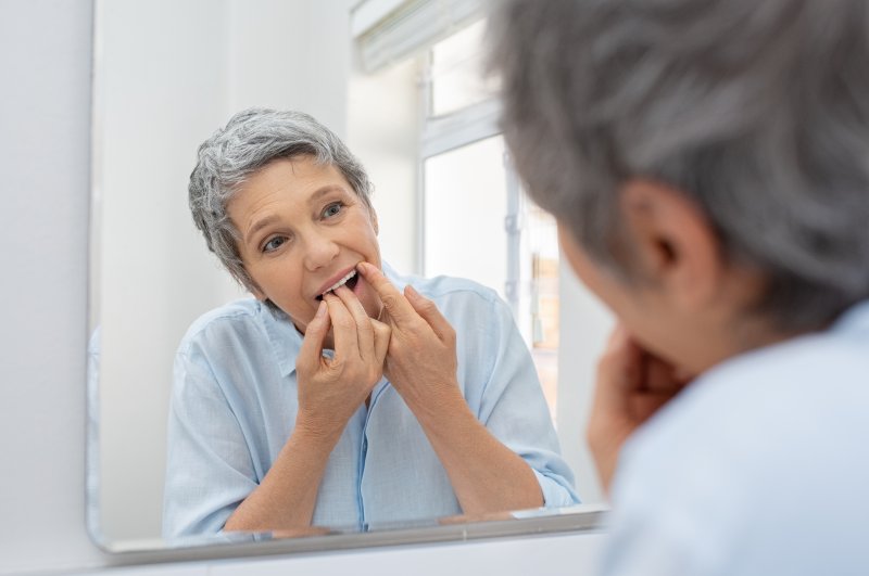 Mature woman with dental implants flossing