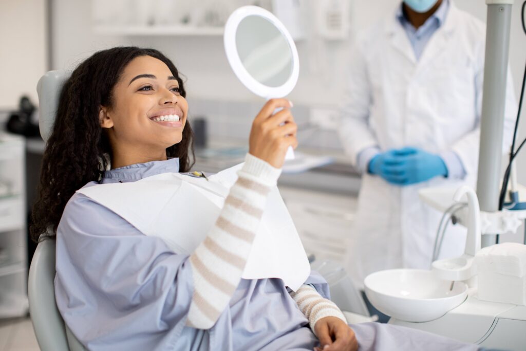 Woman smiling at reflection in handheld mirror